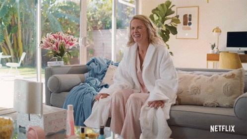 Woman in Bathrobe Sitting on Couch With Netflix Box