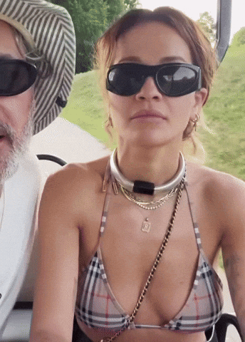 Woman in Bikini and Sunglasses Sitting Next to Man