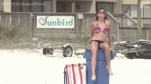 Woman in Bikini Sitting on Trash Can at Beach With Sunbird Sign