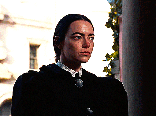 Woman in Black Coat and White Shirt With Medallion Necklace