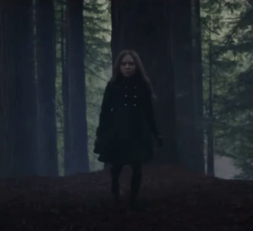 Woman in Black Coat Running Through Forest