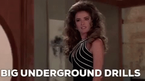Woman In Black Dress In Hallway With Big Underground Drills GIF