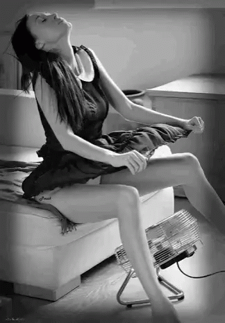 Woman in Black Dress Sitting Next to Fan
