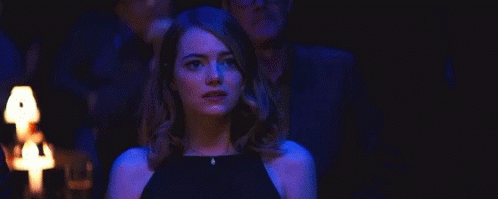 Woman In Black Dress Standing In Dark Room Before Group GIF