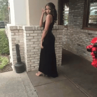 Woman in Black Dress Standing in Front of Brick Building