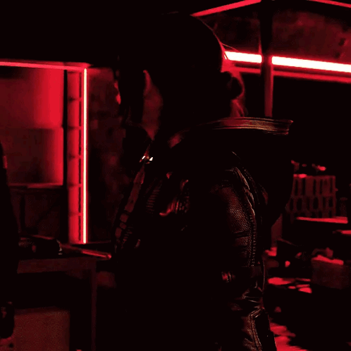 Woman In Black Jacket In Dark Room With Red Lights GIF