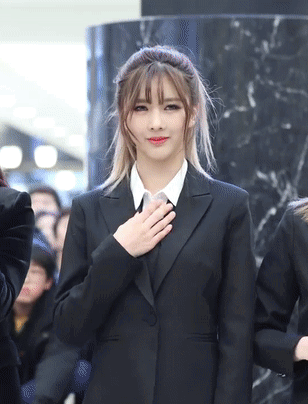 Woman in Black Suit Holding Hand to Heart