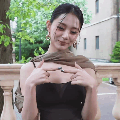 Woman in Black Top Pointing at Breast