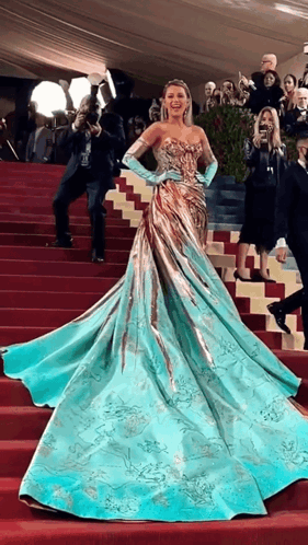 Woman in Blue and Gold Dress Walking Down Stairs