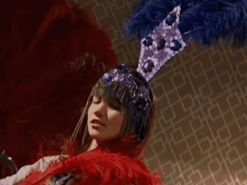 Woman In Blue And Purple Feathered Hat GIF