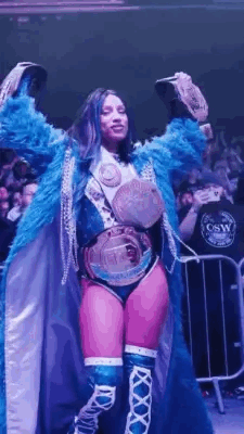 Woman in Blue Coat Holding Two Championship Belts