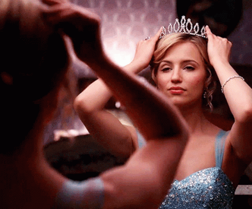 Woman in Blue Dress Adjusting Tiara in Mirror