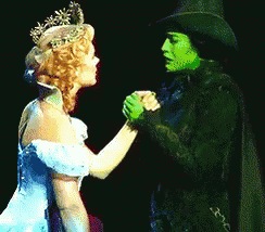 Woman in Blue Dress Holding Hands With Green Woman