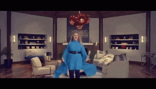 Woman in Blue Dress in Living Room With Couch and Chairs