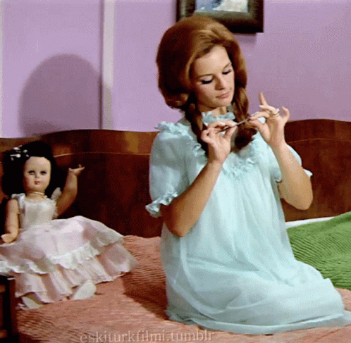 Woman in Blue Dress Sits on Bed Next to Doll Eskiturkfilmi.tumblr