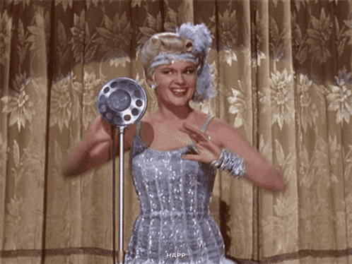 Woman in Blue Dress Smiling at Microphone