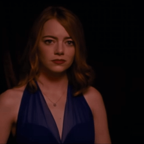 Woman In Blue Dress With Necklace Looking At Camera GIF