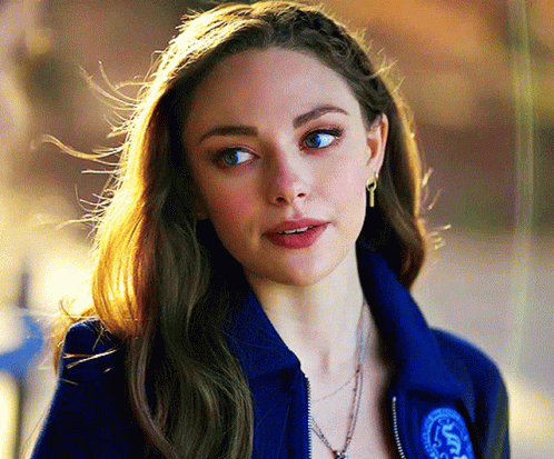 Woman In Blue Jacket And Earrings Looking At Camera GIF