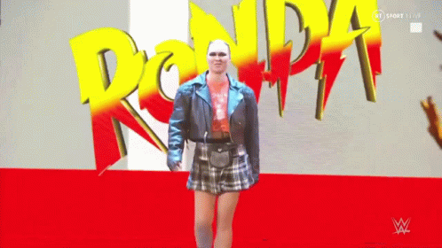 Woman in Blue Jacket and Plaid Skirt in Front of Ronda Sign