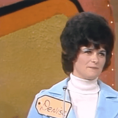 Woman In Blue Jacket And White Turtleneck With Denise Tag GIF