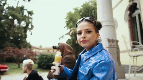 Woman In Blue Jacket Holding Orange Juice GIF