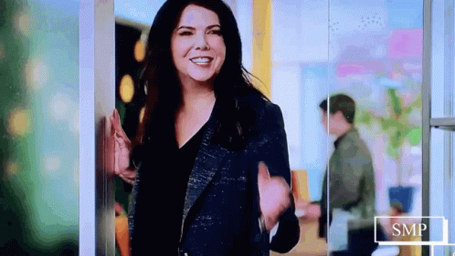 Woman In Blue Jacket Smiling And Waving GIF