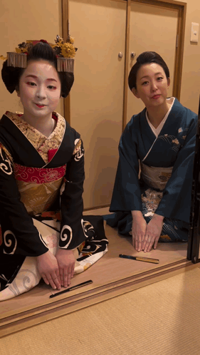 Woman In Blue Kimono Kneeling Next To Woman In Black Kimono GIF