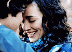 Woman in Blue Scarf Smiling as Man Kisses Forehead