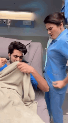 Woman In Blue Scrub And Man In Hospital Bed GIF