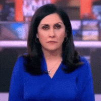 Woman in Blue Shirt and Earrings Looking at Camera