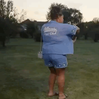 Woman in Blue Shirt and Shorts in Grassy Field