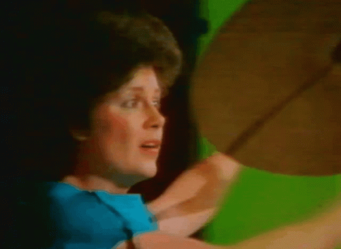 Woman in Blue Shirt Holding Cymbal