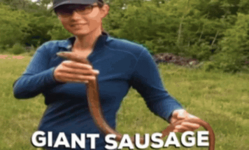Woman In Blue Shirt Holding Giant Sausage GIF