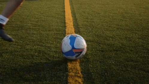 Woman in Blue Shirt Kicking Soccer Ball