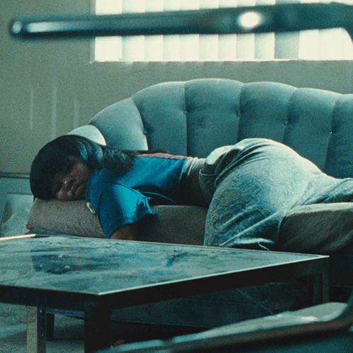 Woman In Blue Shirt Laying On Grey Couch GIF