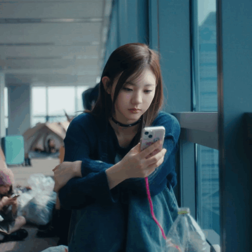 Woman in Blue Shirt Looking at Cell Phone