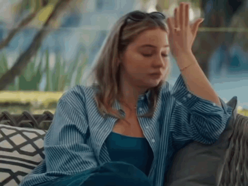 Woman in Blue Shirt Sitting on Couch Hand on Forehead