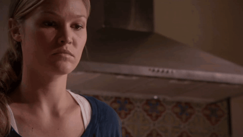 Woman in Blue Shirt Standing in Front of Stove Hood