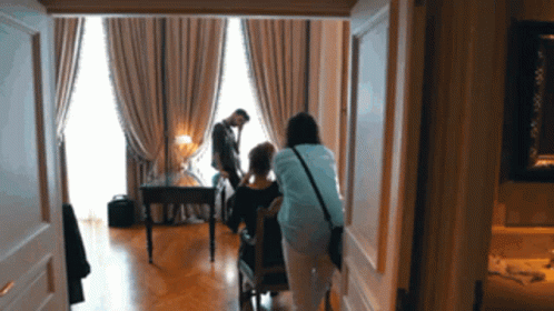 Woman In Blue Shirt Standing Next To Woman In Chair GIF