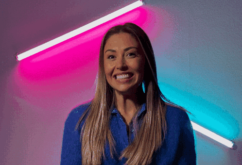 Woman in Blue Smiling in Front of Pink and Blue Background