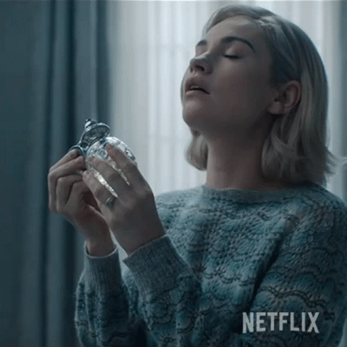 Woman in Blue Sweater Holding Glass With Netflix