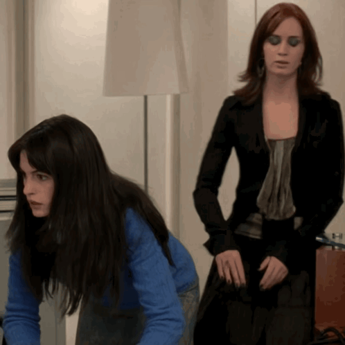 Woman in Blue Sweater Kneeling Next to Woman in Black Jacket