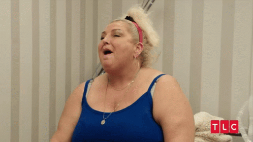 Woman in Blue Tank Top Smiling in Front of TLC Wall