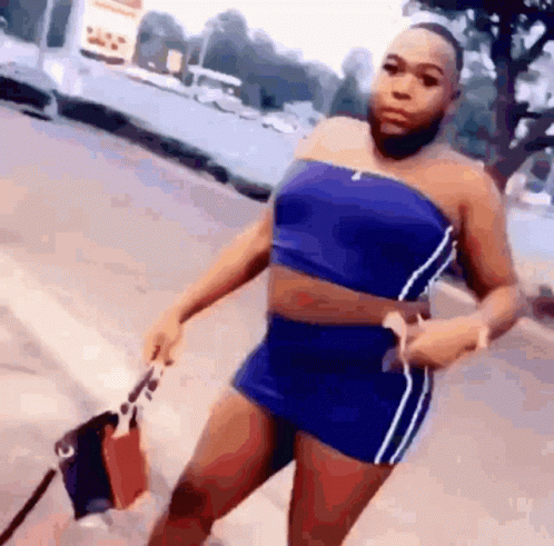Woman in Blue Top and Shorts on Sidewalk