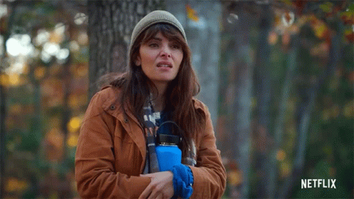 Woman in Brown Jacket Holding Blue Water Bottle in Forest