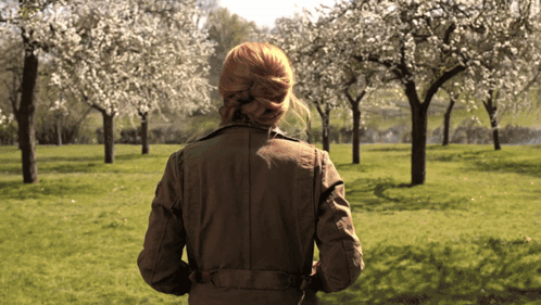 Woman in Brown Jacket Walking Through Blooming Park