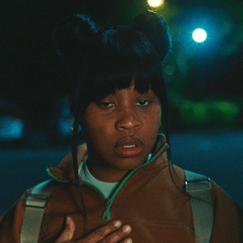 Woman In Brown Jacket With Green Zipper Hand To Chest GIF