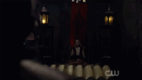 Woman In Costume In Dark Room With CW Logo GIF