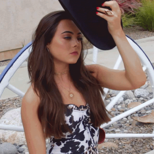 Woman in Cow Print Top Adjusting Black Hat