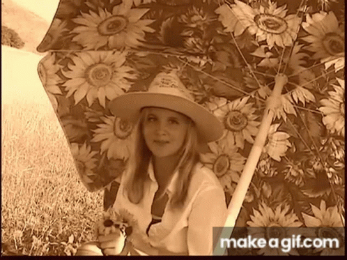Woman in Cowboy Hat Holding Sunflower Under Umbrella
